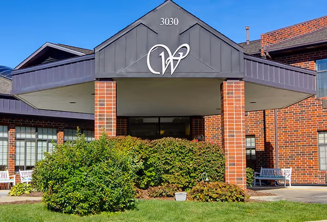 Front entrance of Westgate Assisted Living with brick columns and benches.