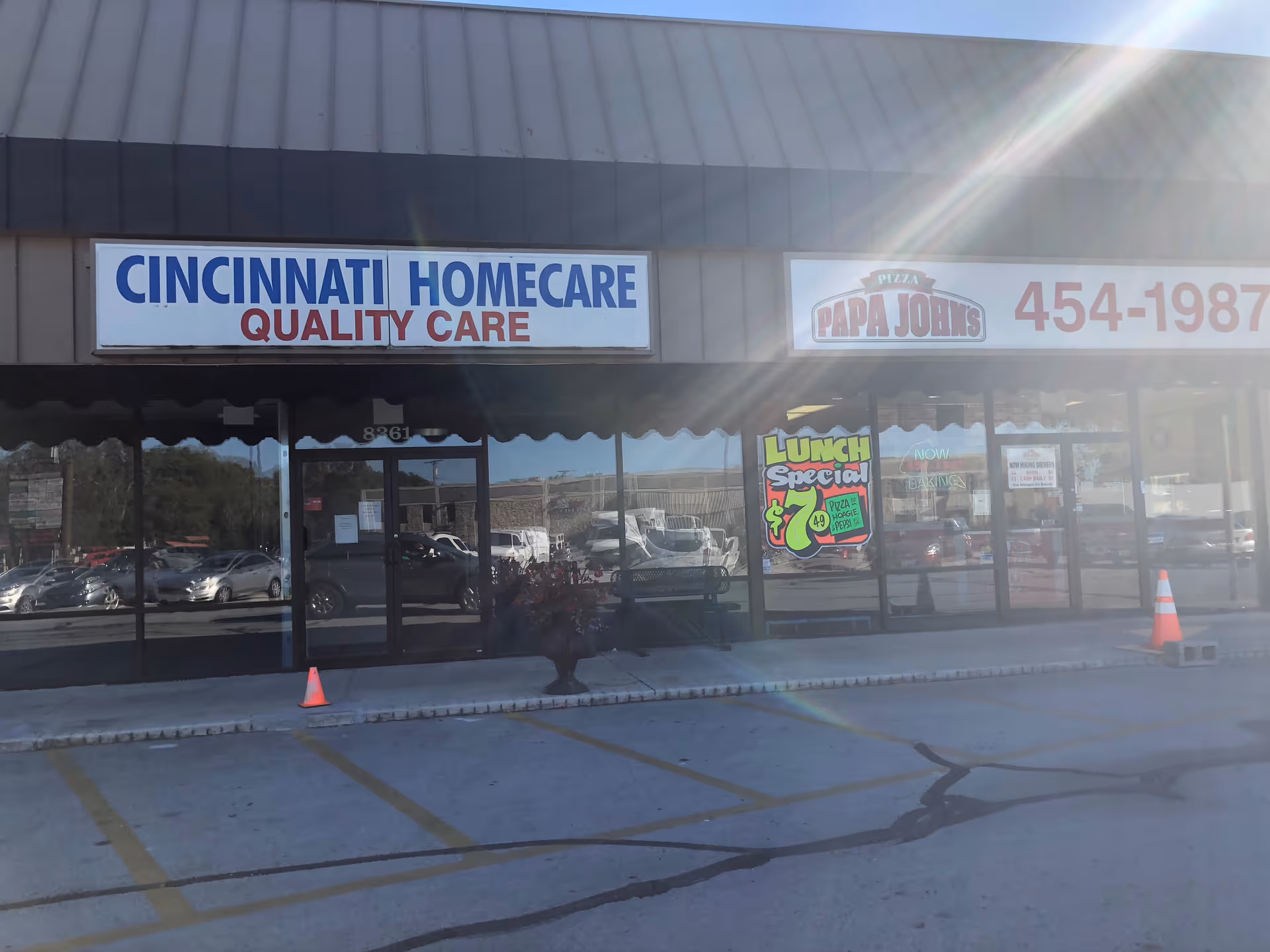 Storefront displays Cincinnati Homecare Quality Care sign with Papa John's sign beside it.
