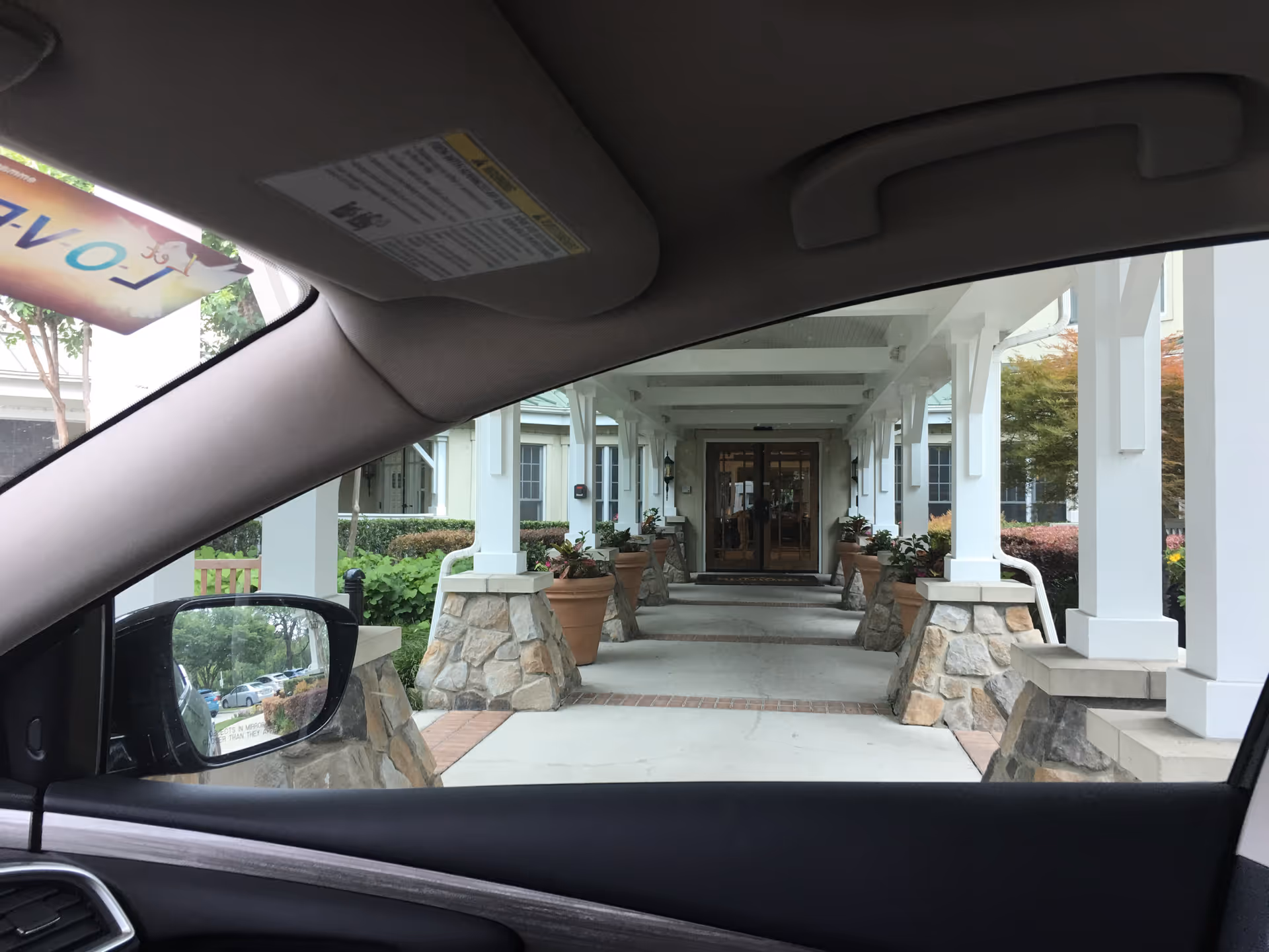 Entrance to Sunrise on Hillcrest, a sheltered walkway with white columns and planters.