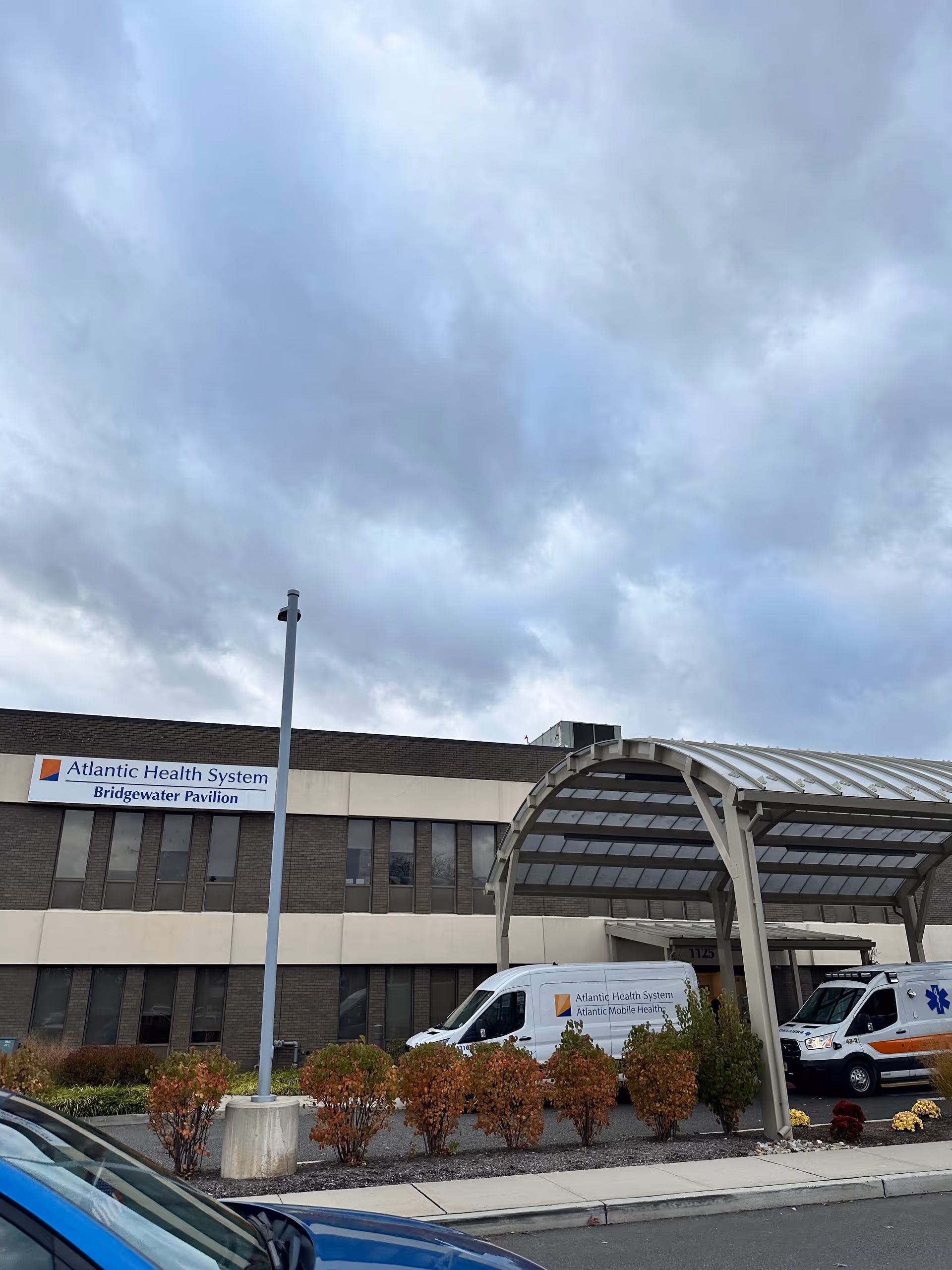 Exterior view of Atlantic Health System Bridgewater Pavilion with ambulances under a curved canopy.