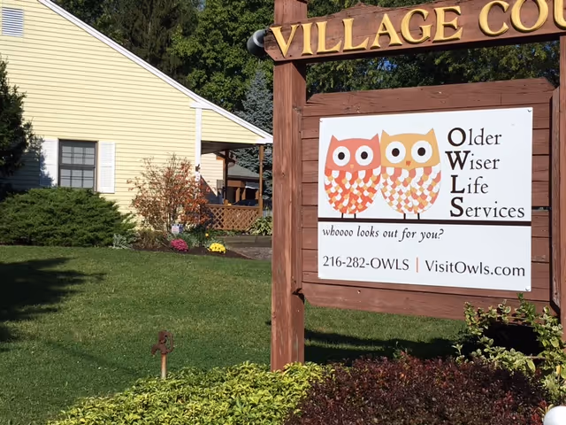 Exterior view of Older Wiser Life Services facility with a wooden signboard.