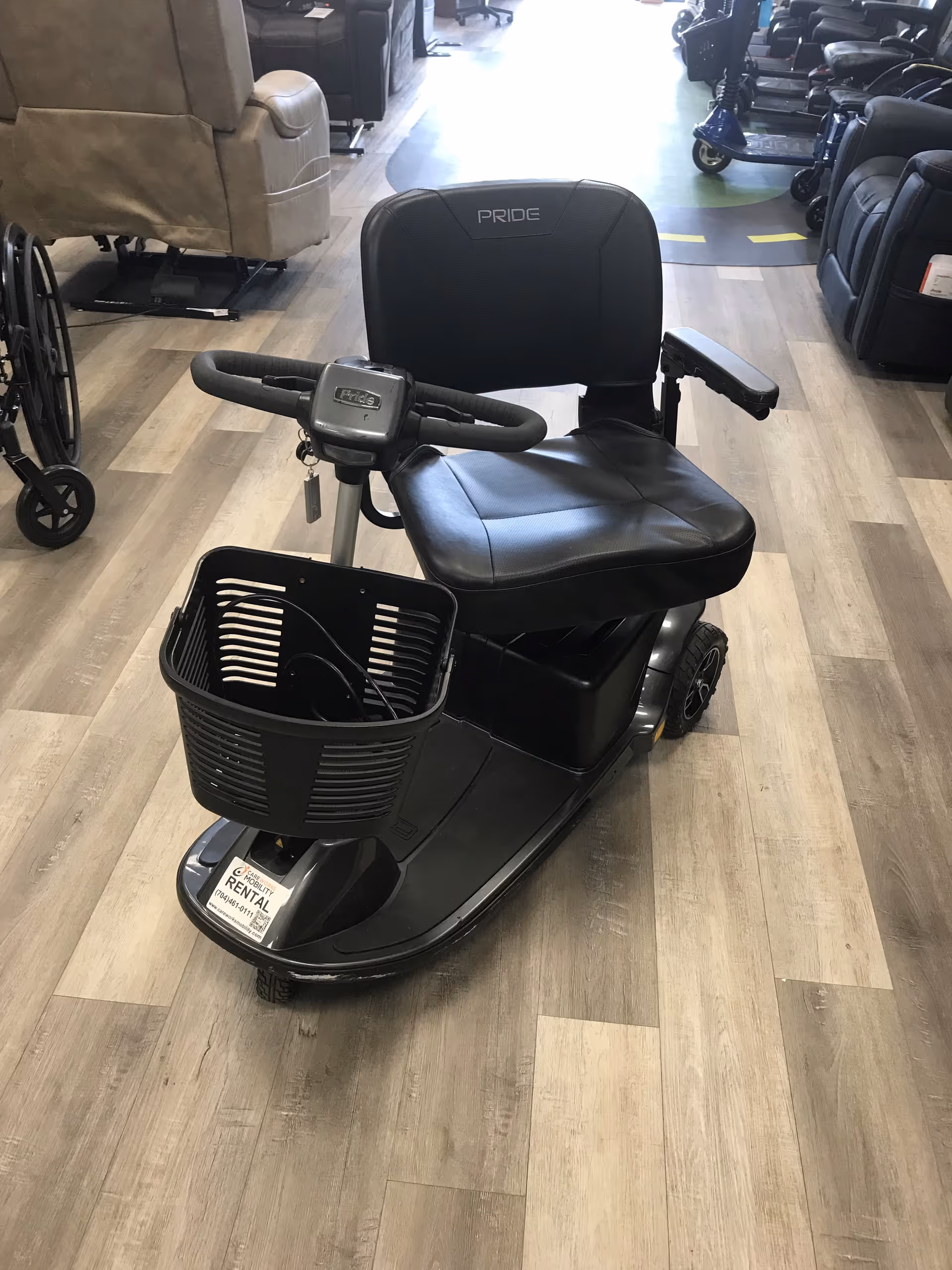 Indoor showroom at Careworks Mobility featuring a black Pride mobility scooter with front basket.