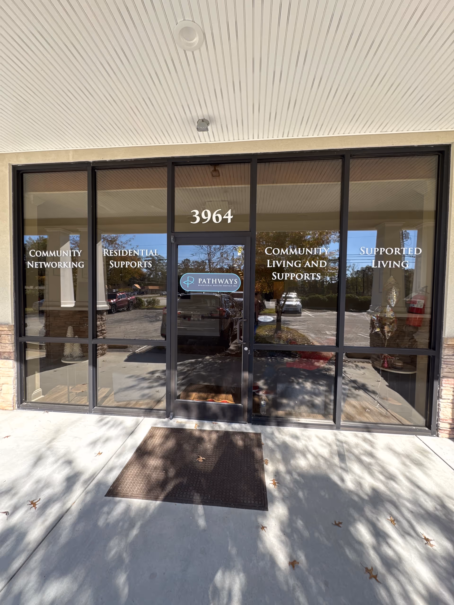 Front entrance of Pathways facility with glass doors labelled 3964 and program signs.