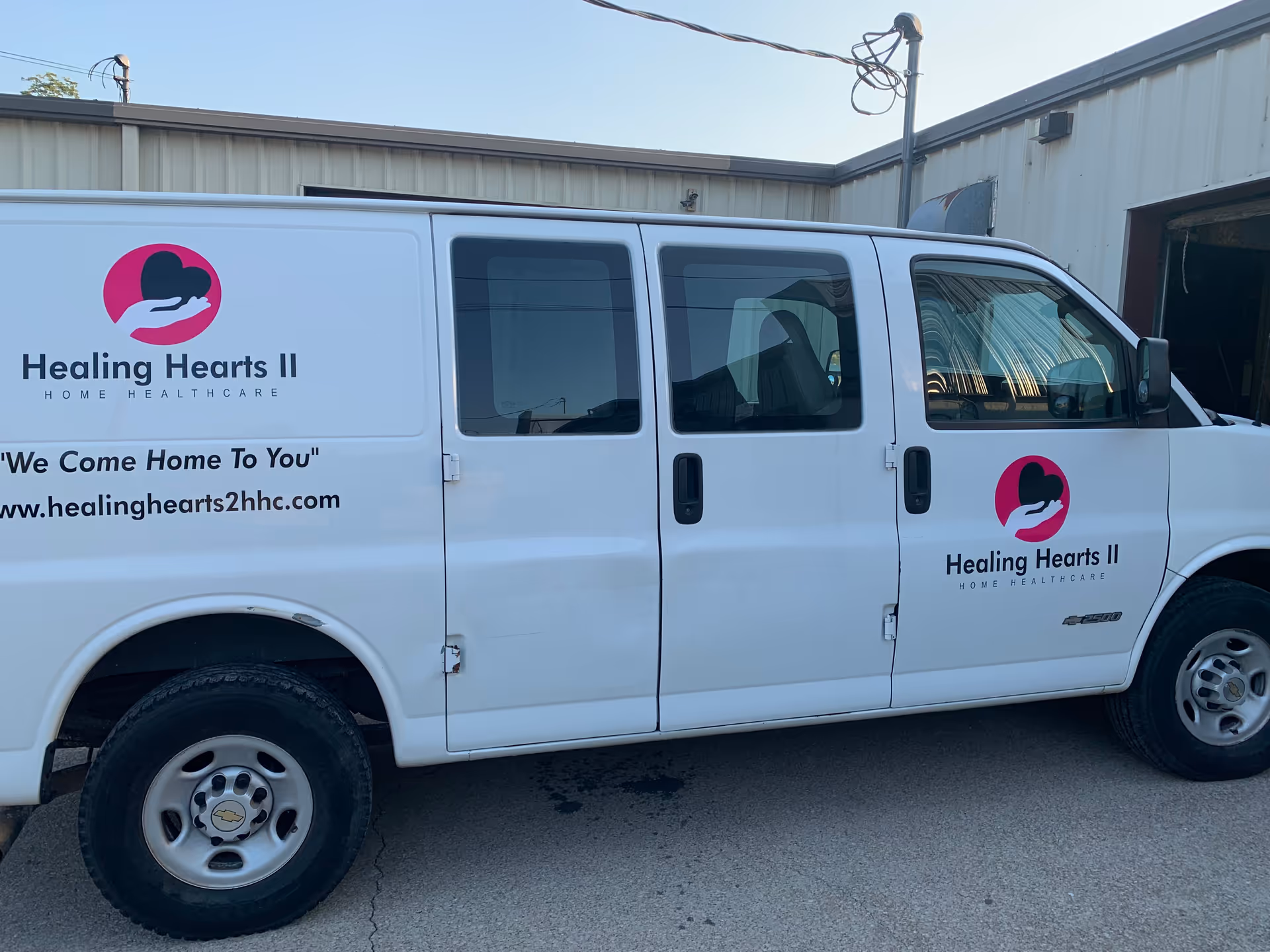 White Healing Hearts II Home Healthcare van with logo parked outside facility.
