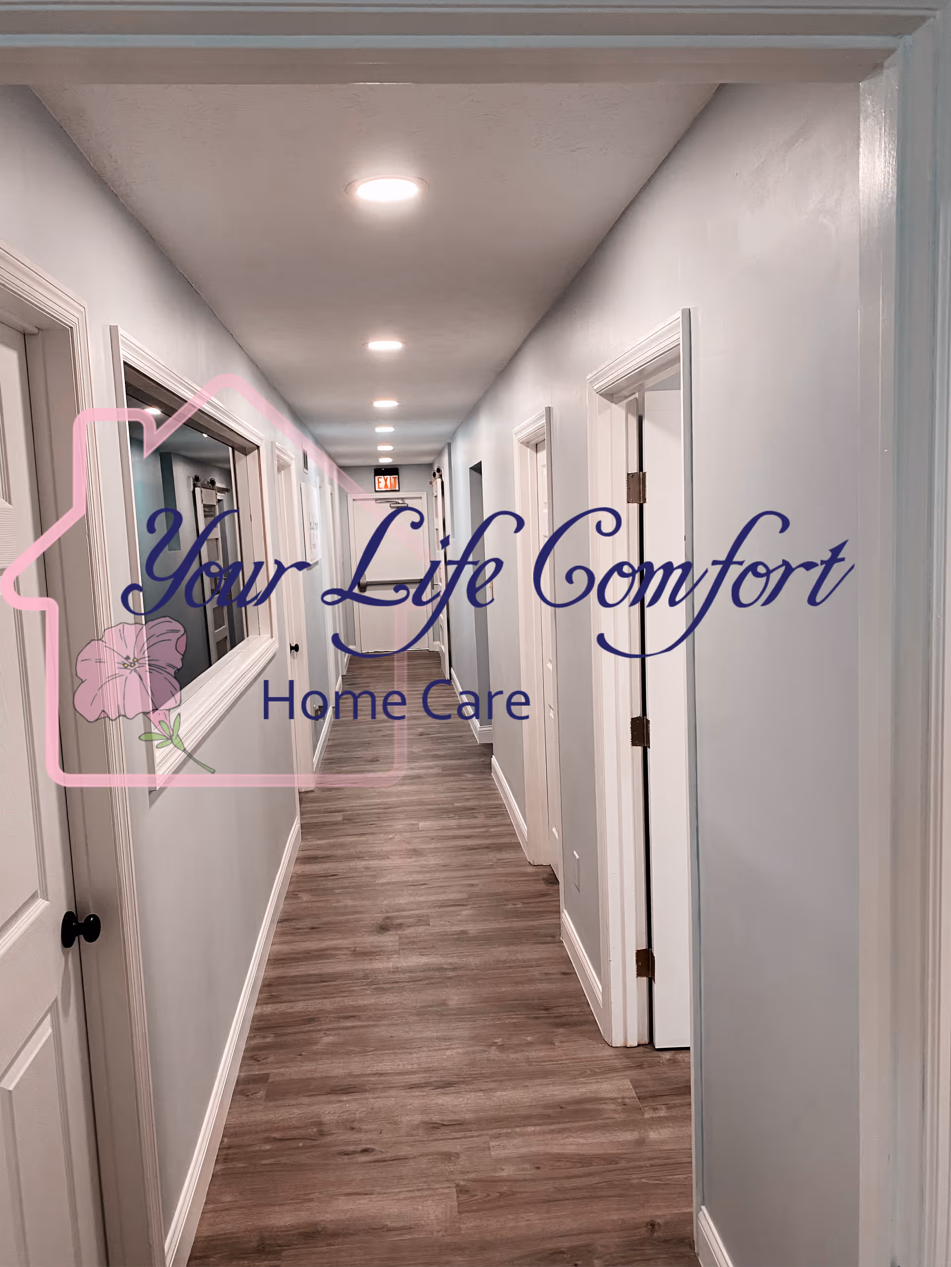 Narrow interior hallway of a senior care facility with white walls and closed doors.