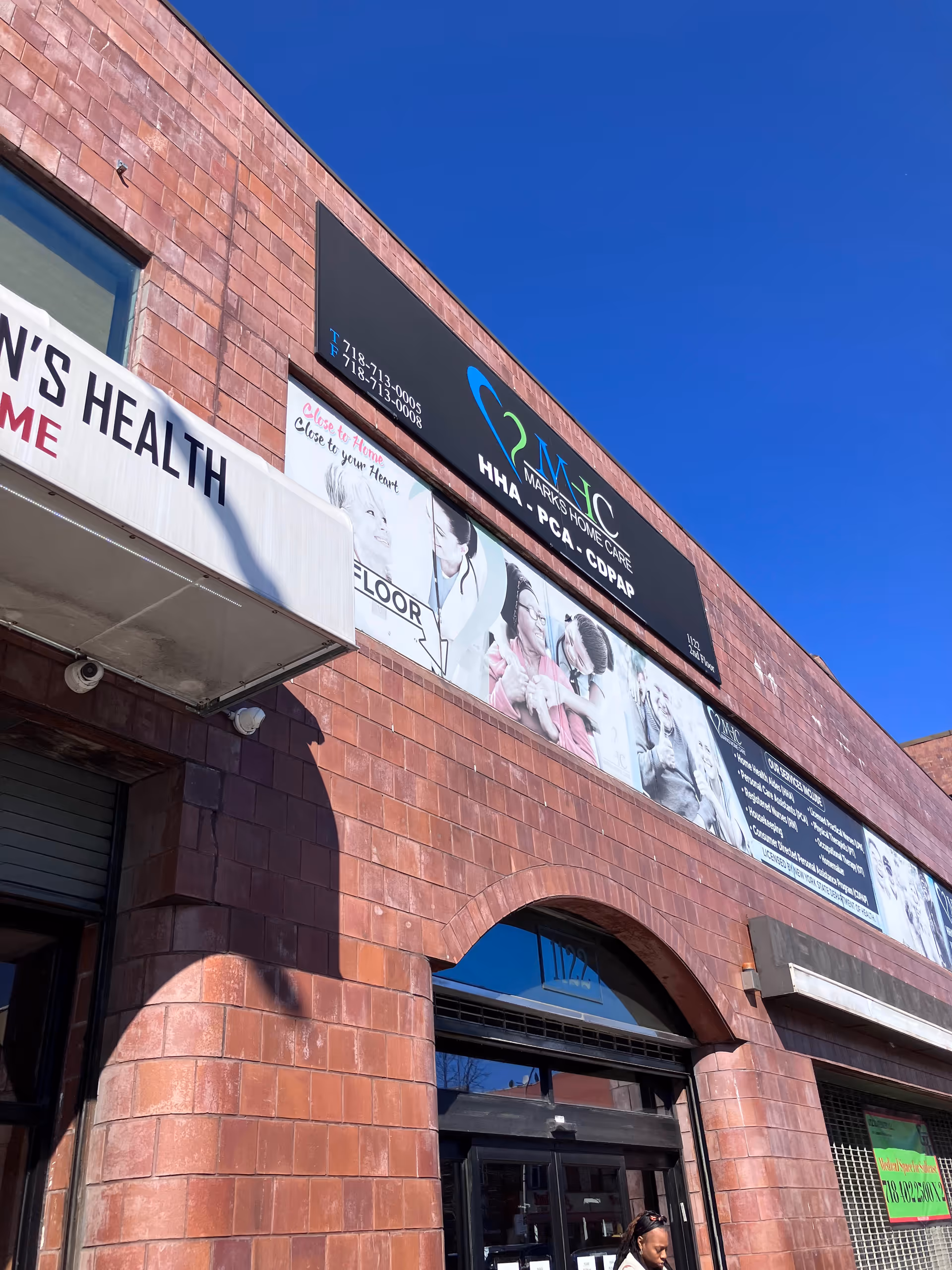 Brick building exterior with Marks Home Care (Coney) signage against a clear blue sky.