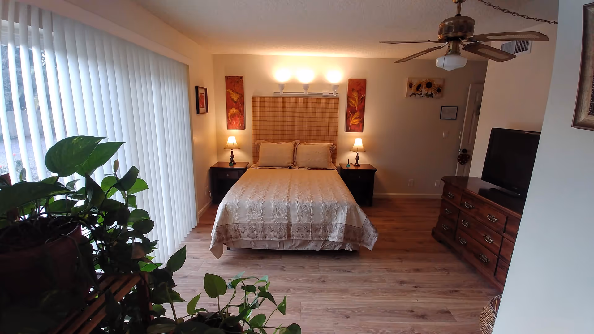A cozy bedroom in a senior living suite with bed, nightstands, and TV.