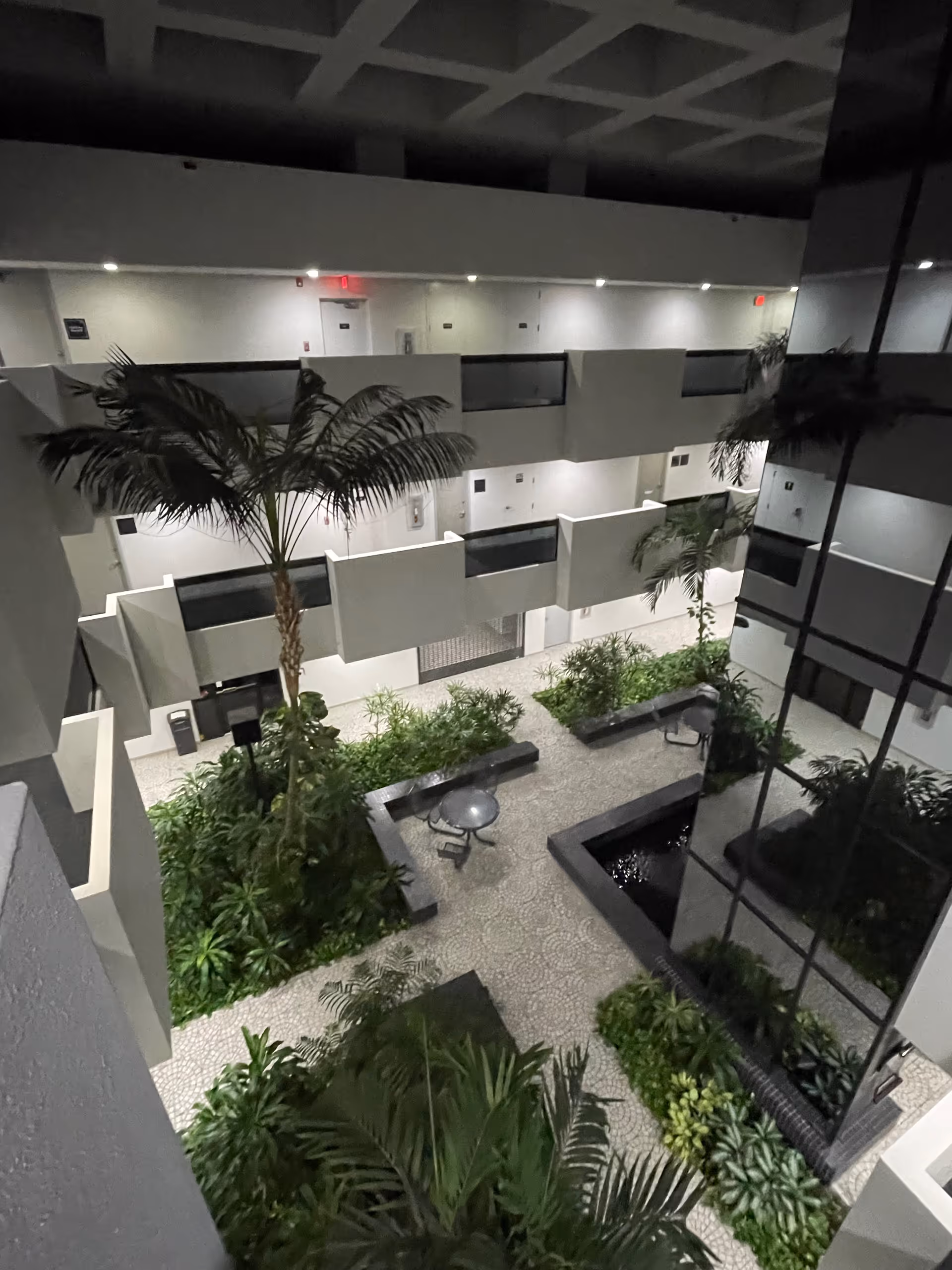Multi-story indoor atrium with balconies, plants, and seating in a modern senior living facility.
