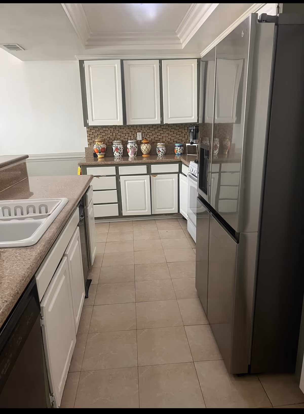 A tidy kitchen with white cabinets, beige countertops, and stainless appliances.