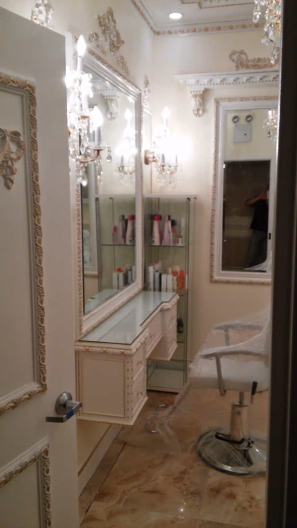 Ornate vanity area with mirrors, lighting, and a white styling chair