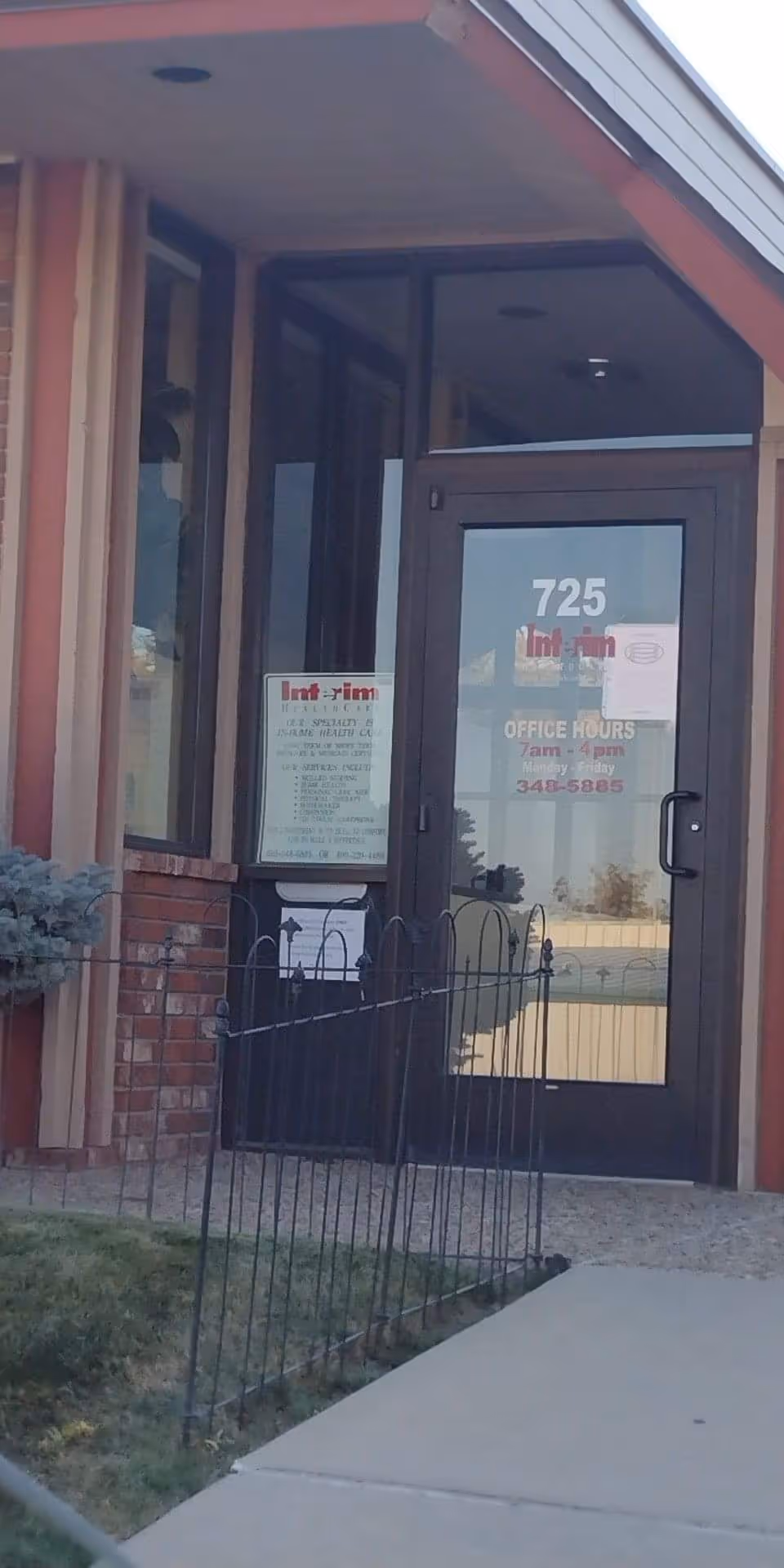 Building entrance with glass door and address number 725, small black railing in foreground.