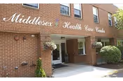 Exterior view of Middlesex Health Care Center entrance on brick building with hanging plants.