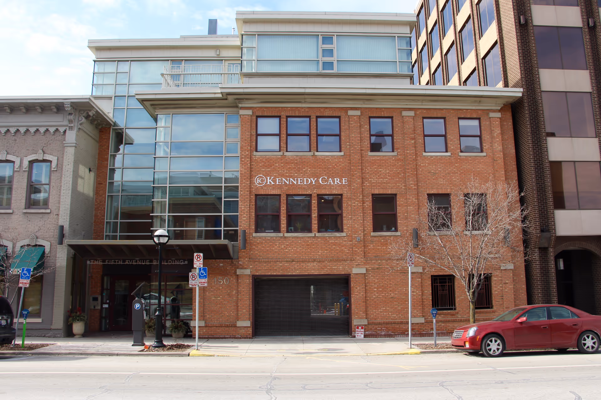 Brick Kennedy Care building with glass entrance on a busy city street.