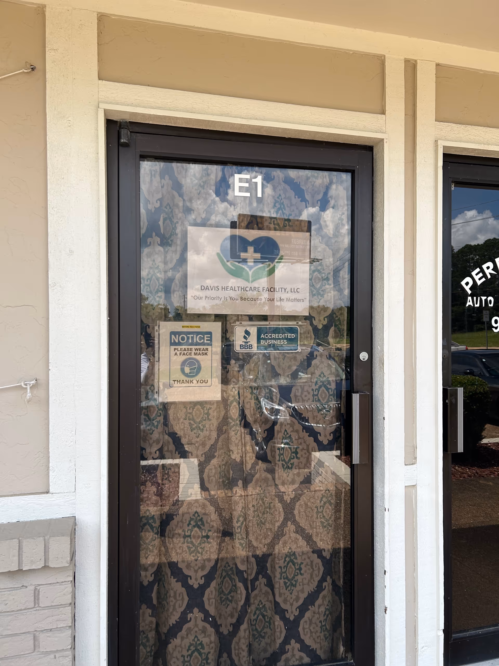 Front entrance door of Davis Healthcare Facility with notices and logos.