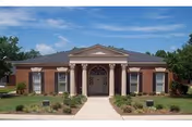 Brick senior living facility front with arched entrance and well-kept landscaping