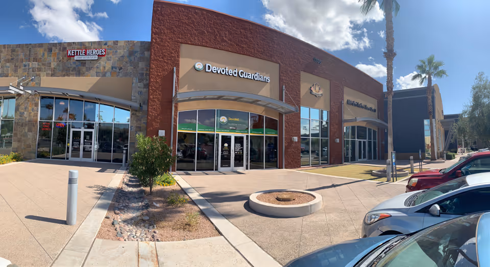 Exterior view of Devoted Guardians Home Care entrance in a strip mall, with parked cars.