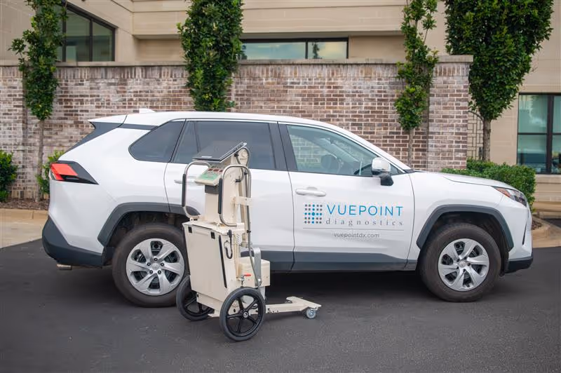 White SUV with Vuepoint Diagnostics branding parked outside a brick building.