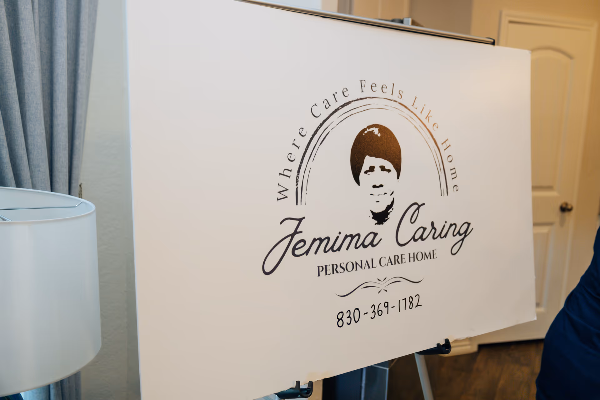 Indoor sign displaying Jemima Caring Personal Care Home logo and contact number.