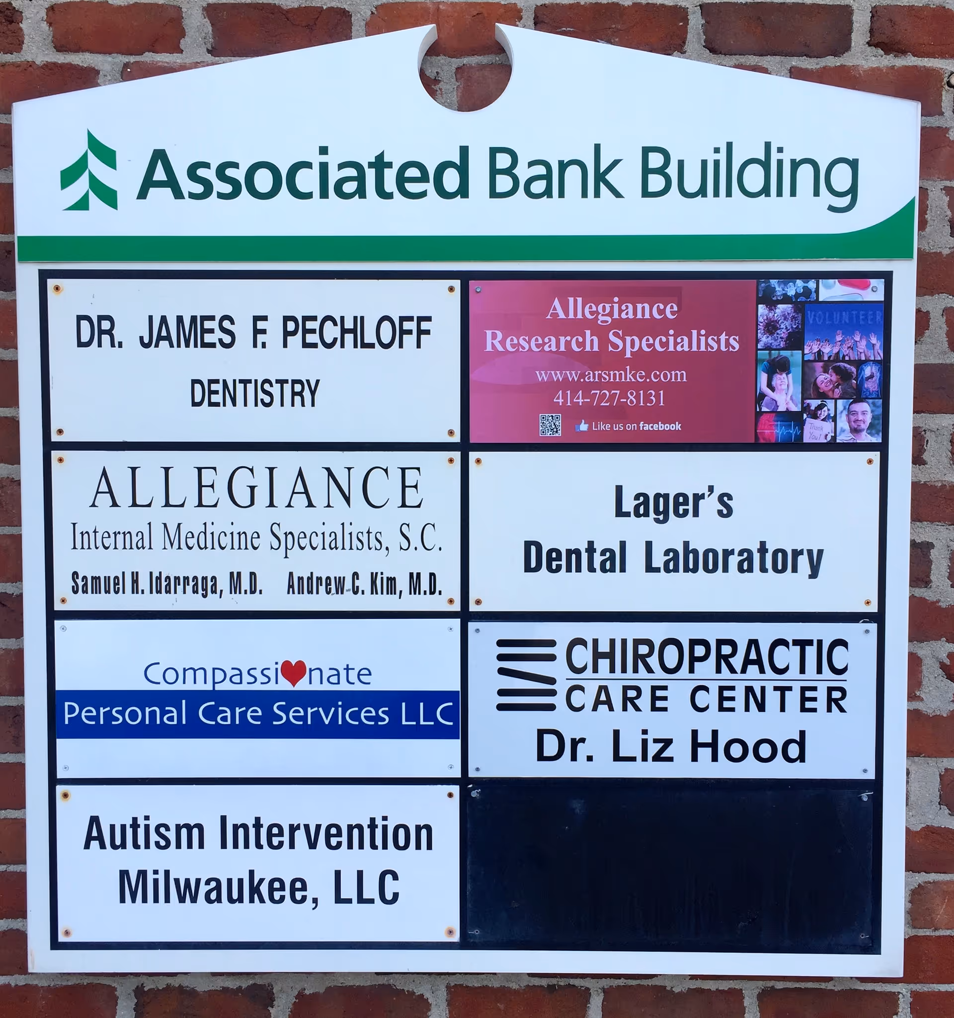 Exterior signboard on brick wall listing multiple tenants under Associated Bank Building.