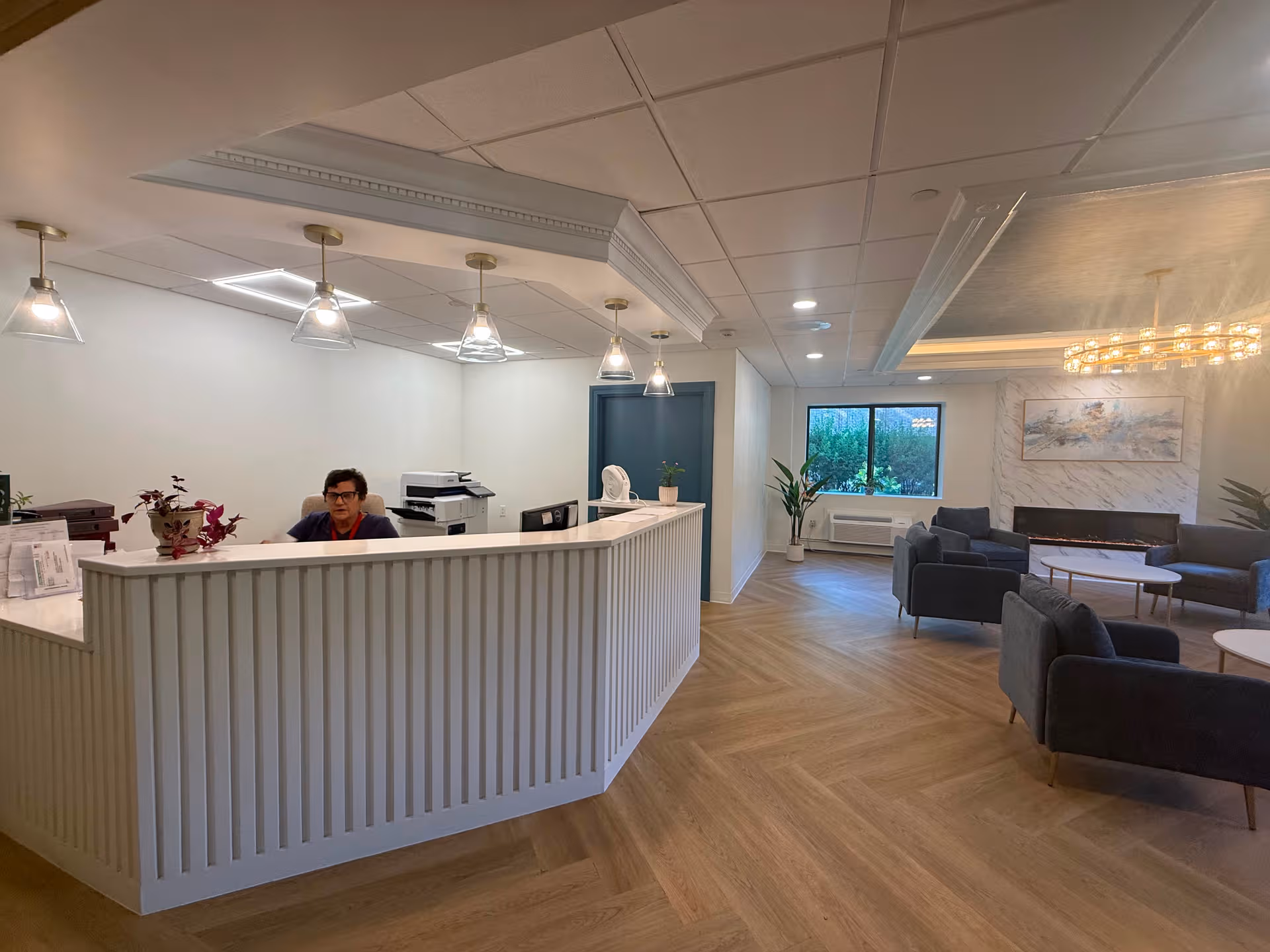 Reception desk with staff and a seating lounge in a bright, modern senior living lobby.