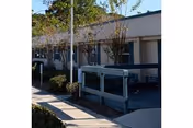 Exterior of Solaris Healthcare Merritt Island with a walkway, railing, and landscaped shrubs along the building.
