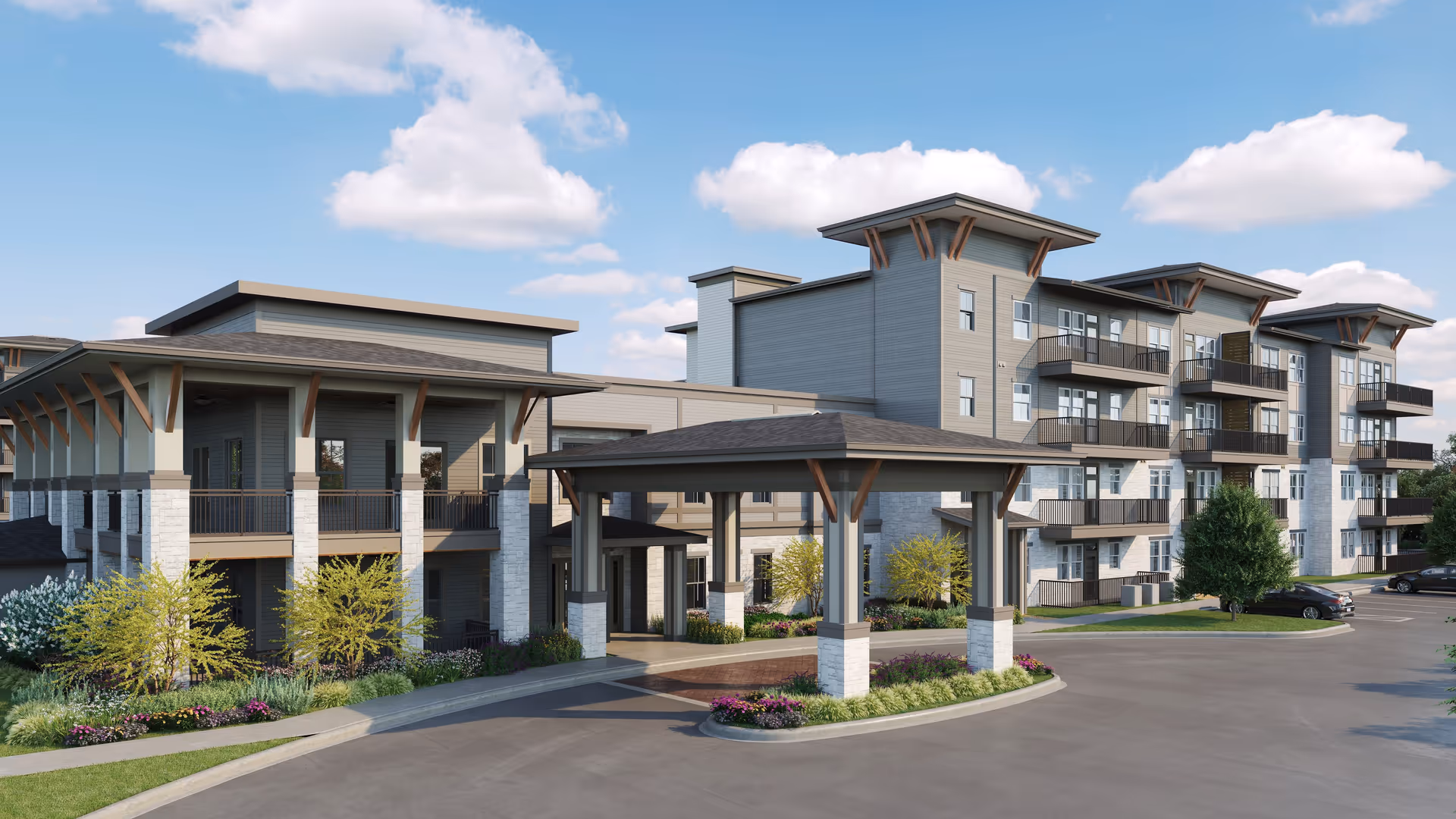 Exterior view of a modern senior living facility building with multiple floors, balconies, and a covered entrance area. The building is surrounded by landscaped greenery and a parking area under a partly cloudy sky.