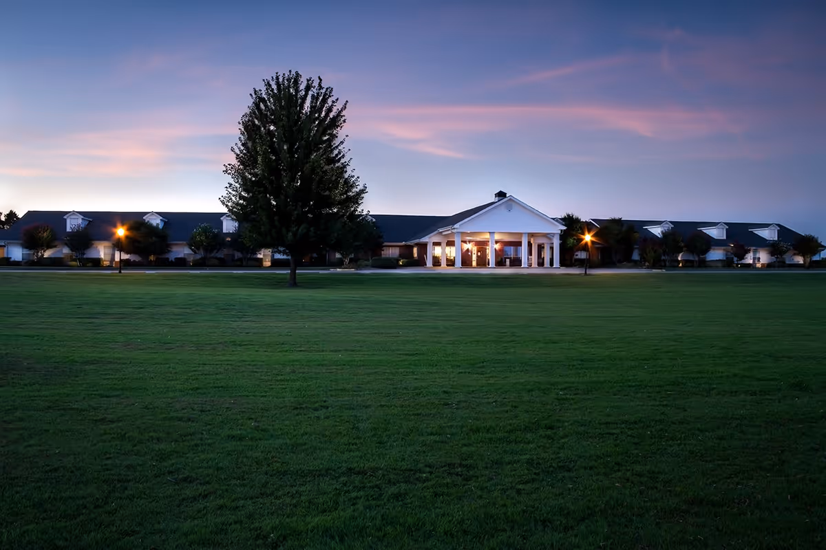 Wide exterior view of Greenhurst Nursing Center at dusk, with a large lawn and entrance.