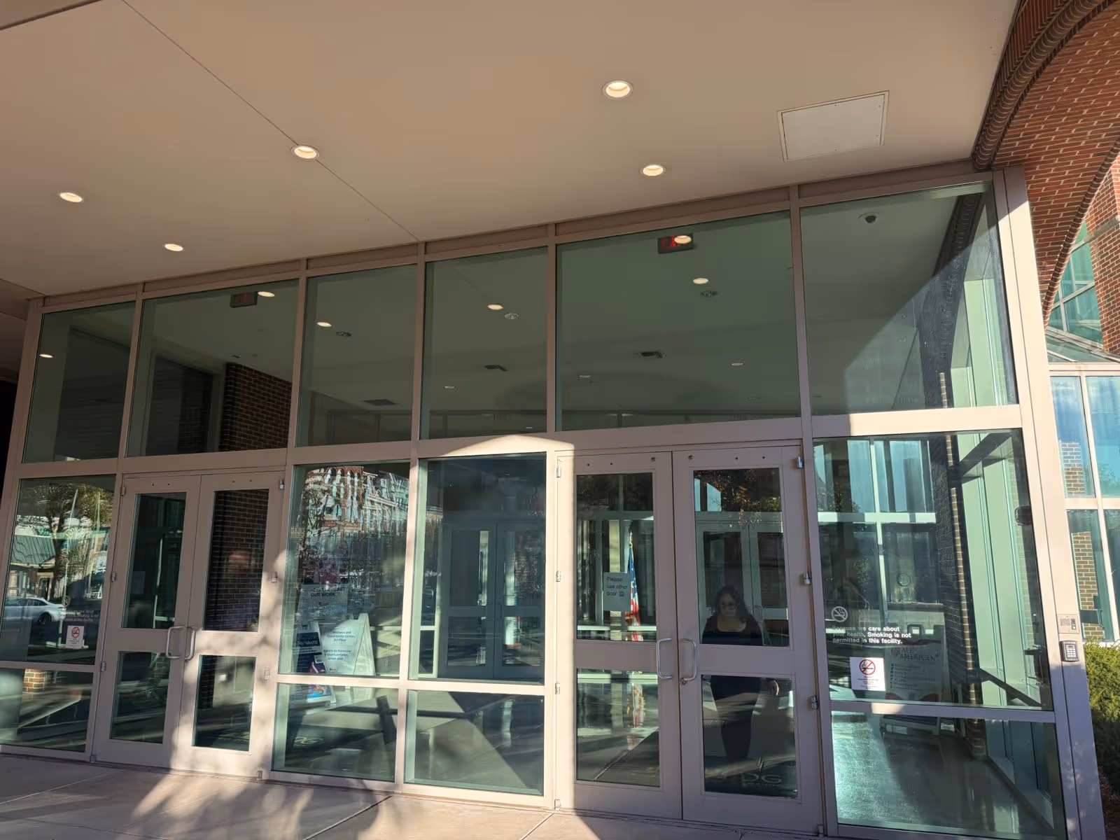Glass-front entrance of a senior living facility with large doors and windows.