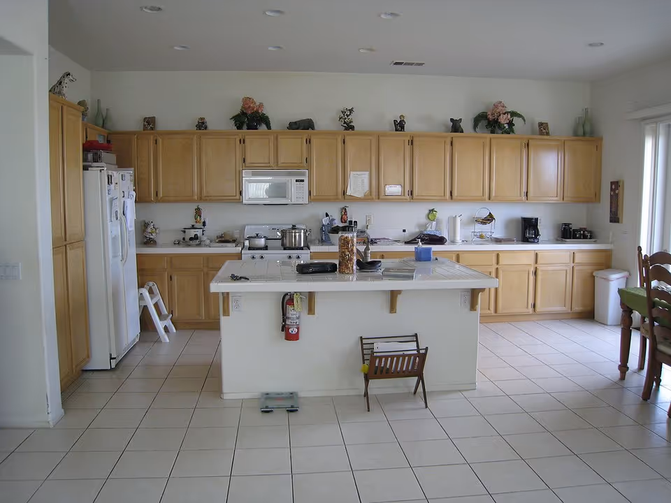 Bright senior living facility kitchen with wooden cabinets, a white island, and appliances along the wall