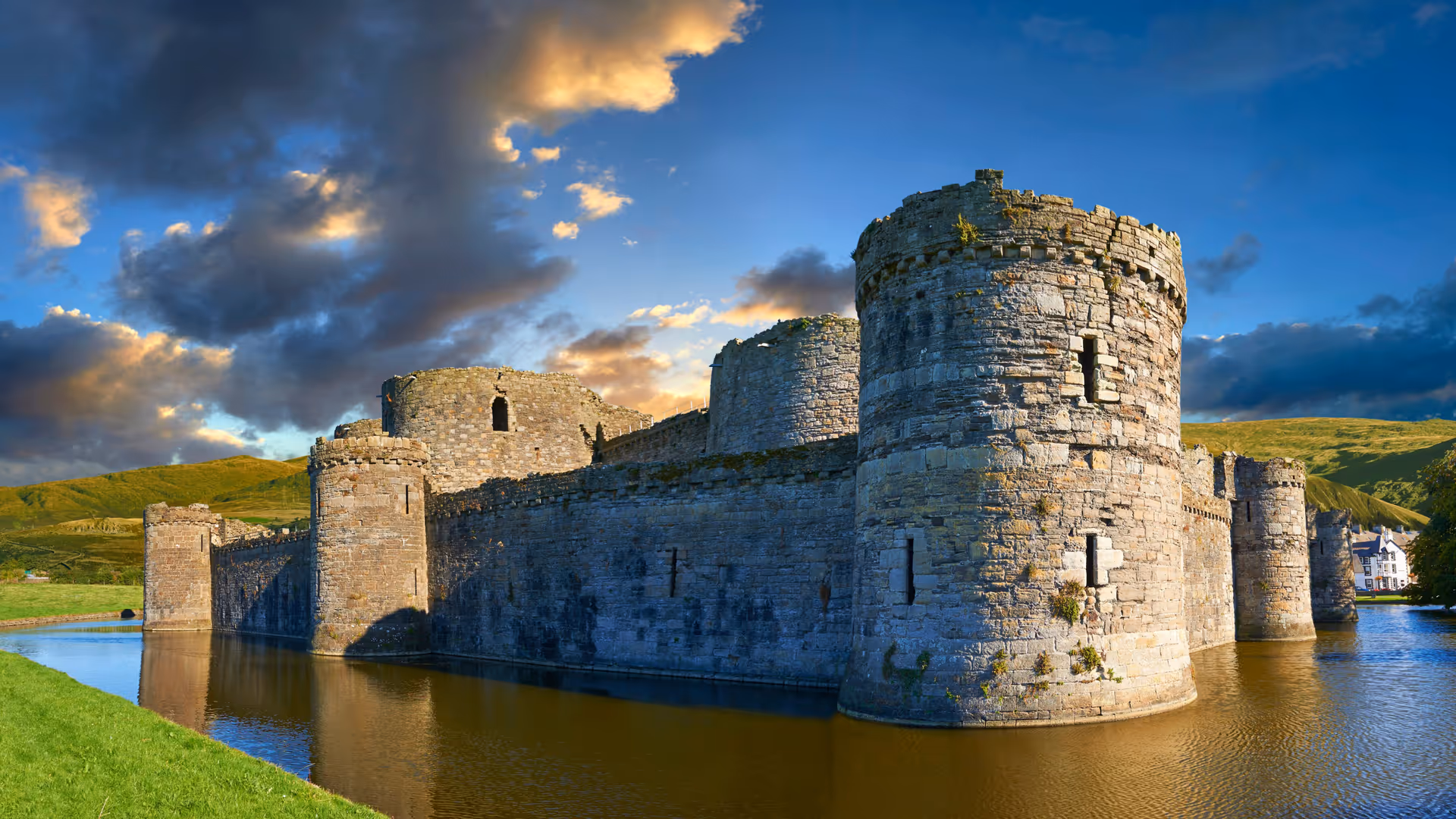 Historic stone castle with round towers set in a moat under blue sky.