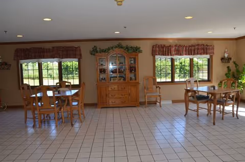 Bright dining room with wooden tables, chairs, and a china cabinet.