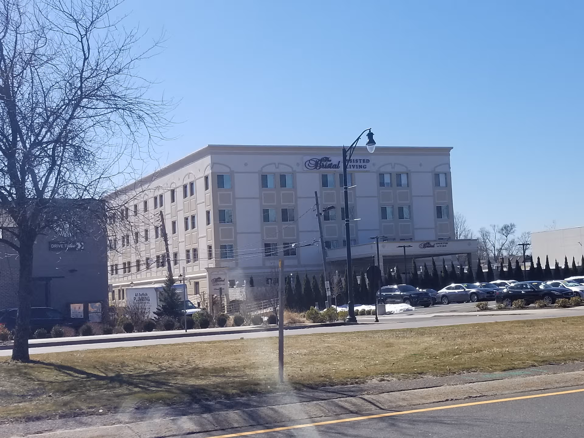The Bristal Assisted Living at Lynbrook building along a street with parked cars.