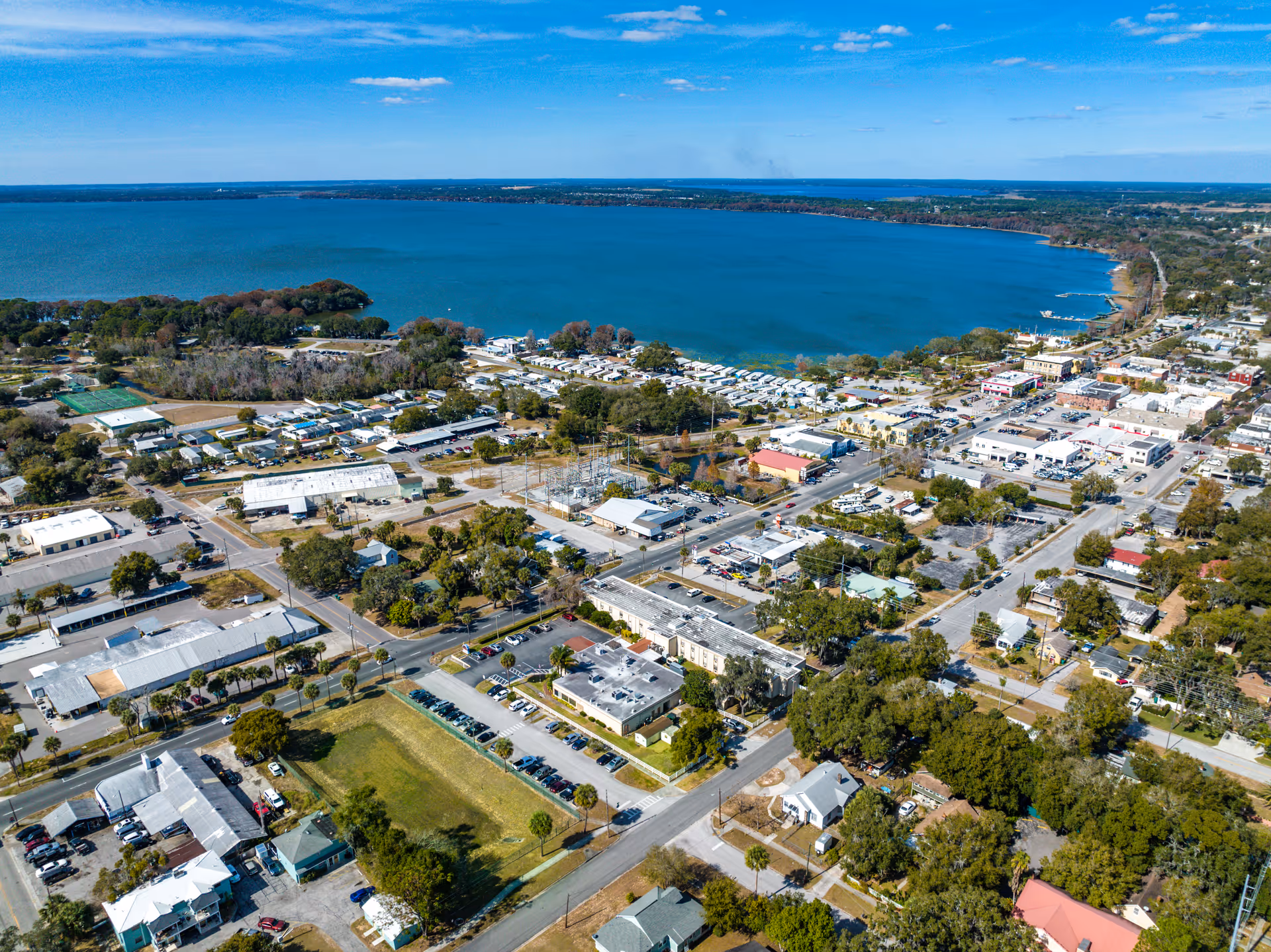Aerial view of a coastal town with a bay, roads, and residential buildings.