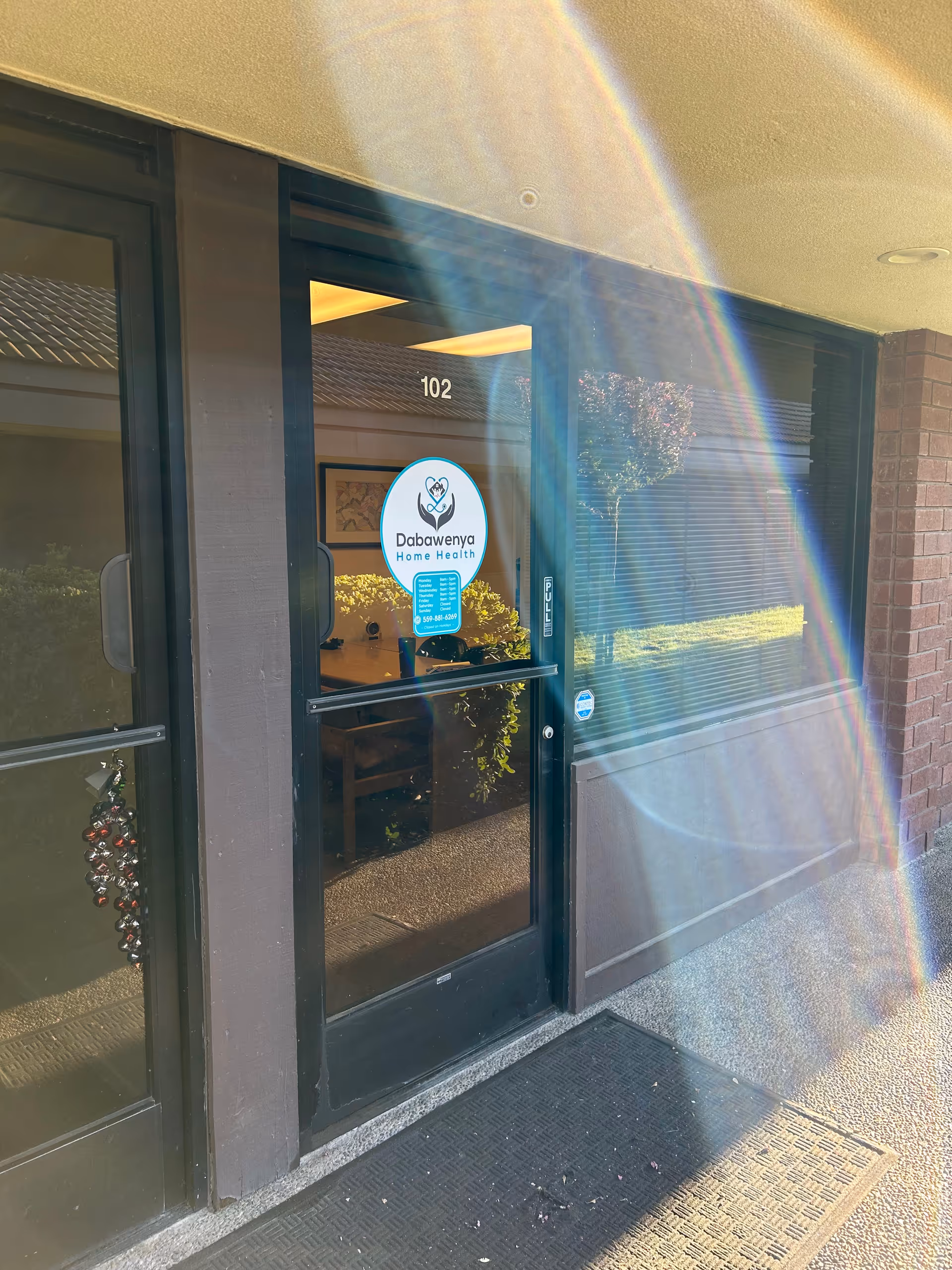 Glass front entrance with rainbow arc, door 102, Dabawenya Home Health sign.