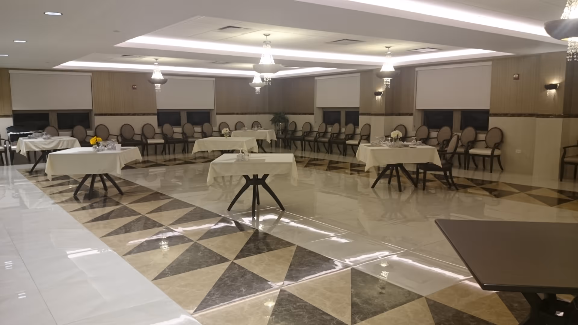 A spacious, well-lit dining room with tables set for meals in a senior facility.