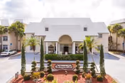 Front entrance of The Veranda Club senior living facility with a driveway, landscaped circular planter and sign.
