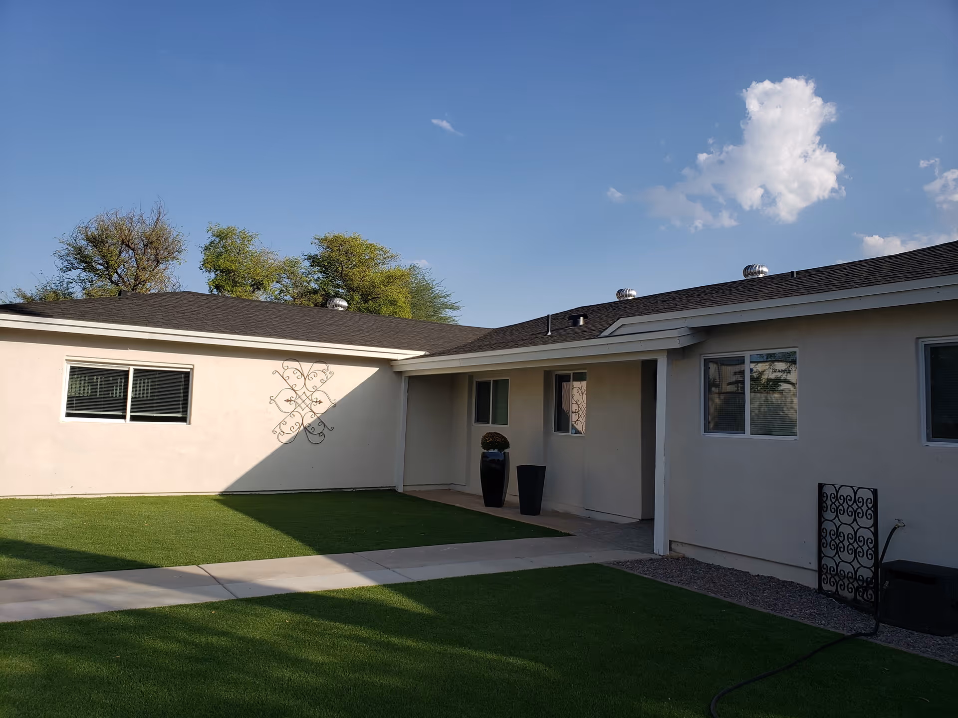 Single-story Sunrise Care Homes Paradise Valley exterior with green lawn, windows, and decorative metal art.