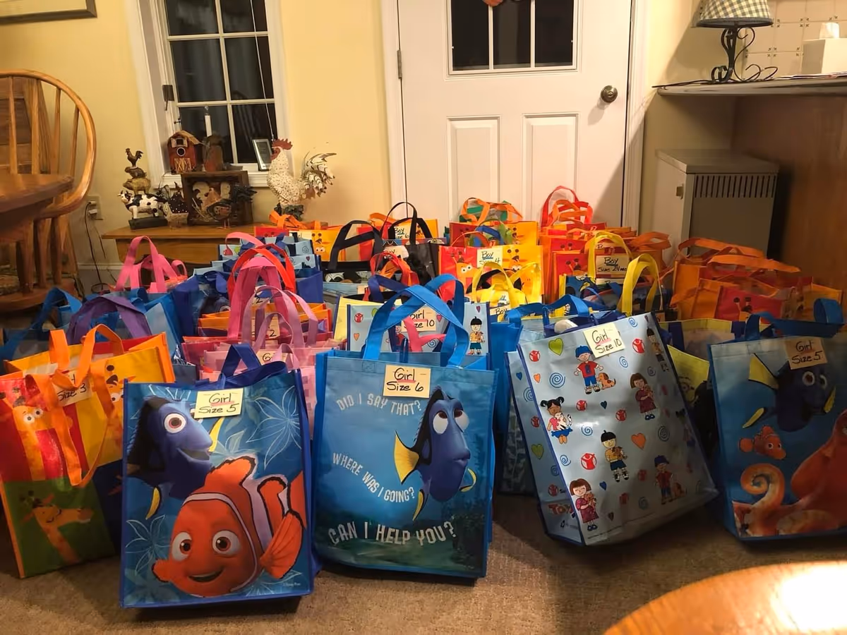 Colorful gift bags arranged on a carpeted living room floor near a white door.