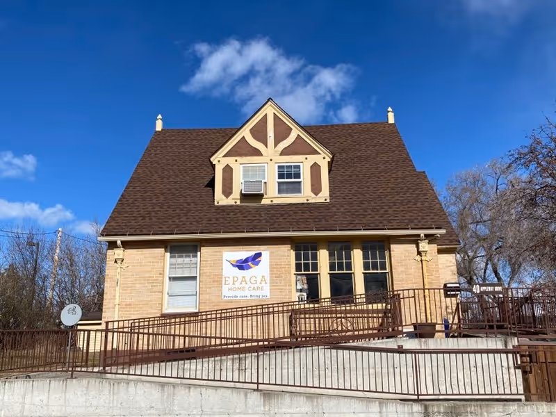 Front view of EPAGA Home Care building with brick facade, peaked roof, and ramp.
