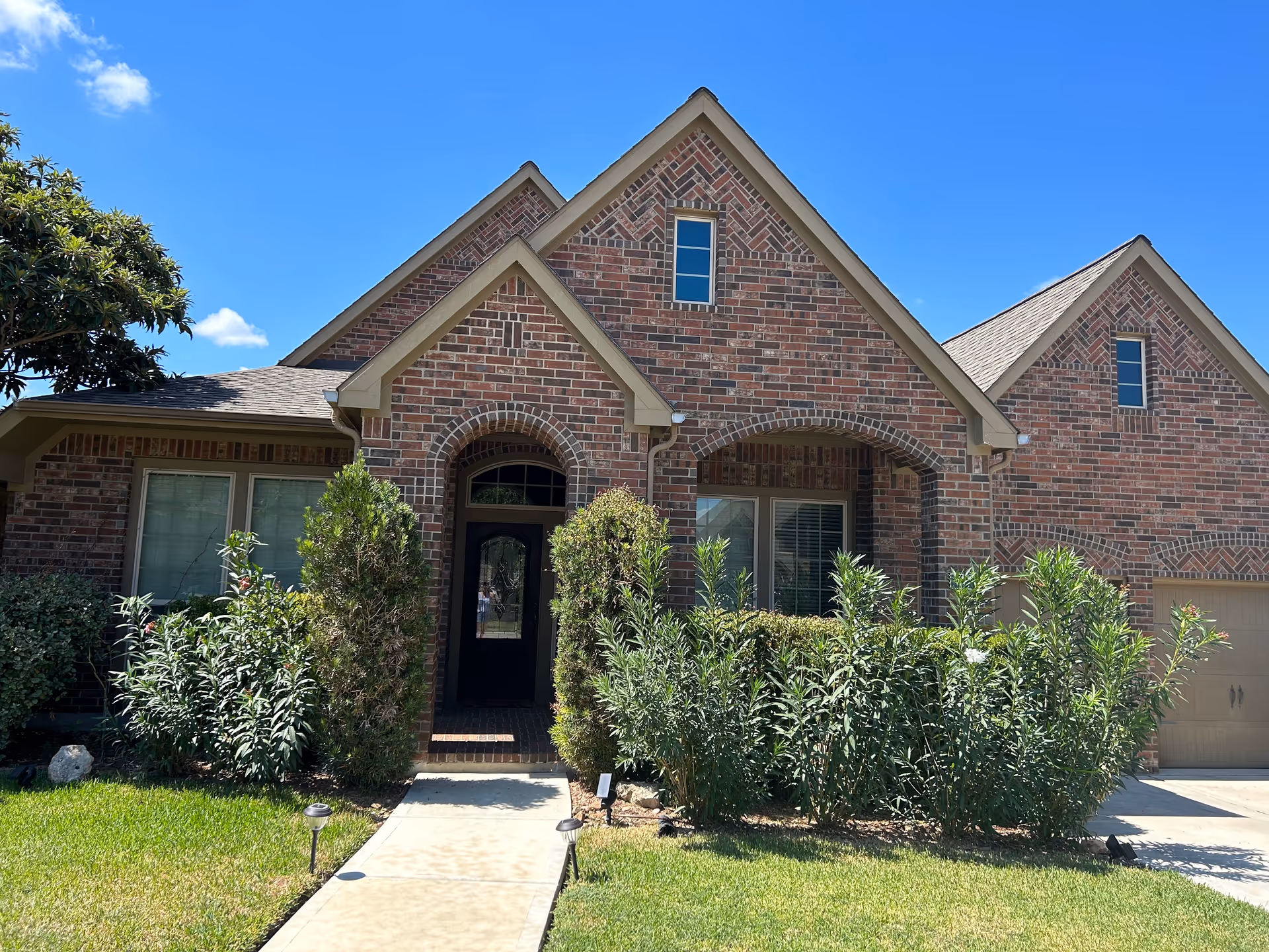Brick senior living home front entry with arched doorway and manicured landscaping.