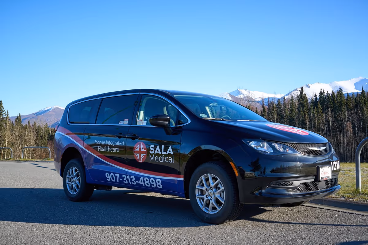 Black SALA Medical transport van parked on a road with mountains behind