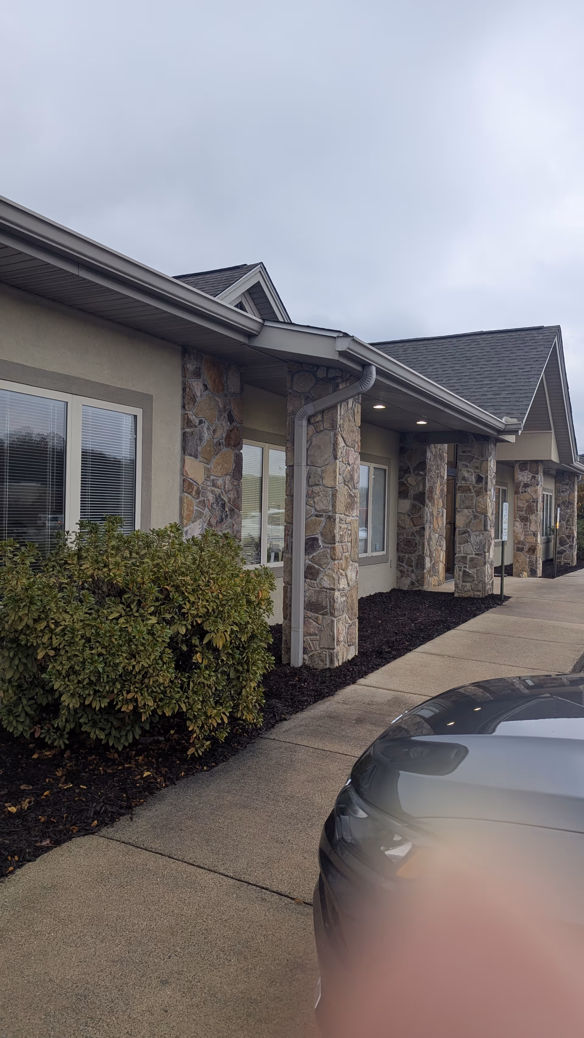 Exterior view of PruittHealth @ Home (Blue Ridge) building with stone columns and shrubs.