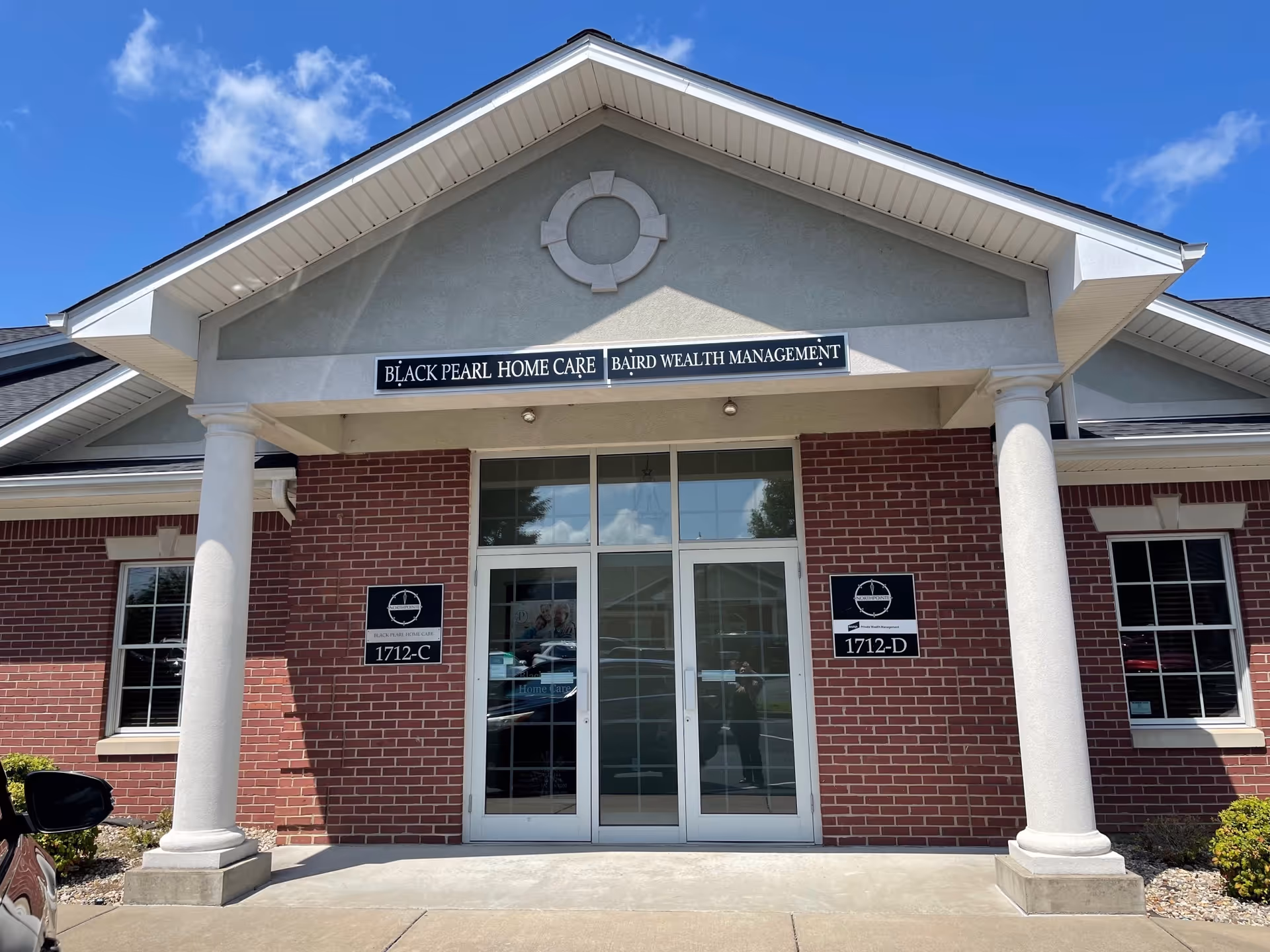 Brick building with white columns and a glass entry labeled Black Pearl Home Care.