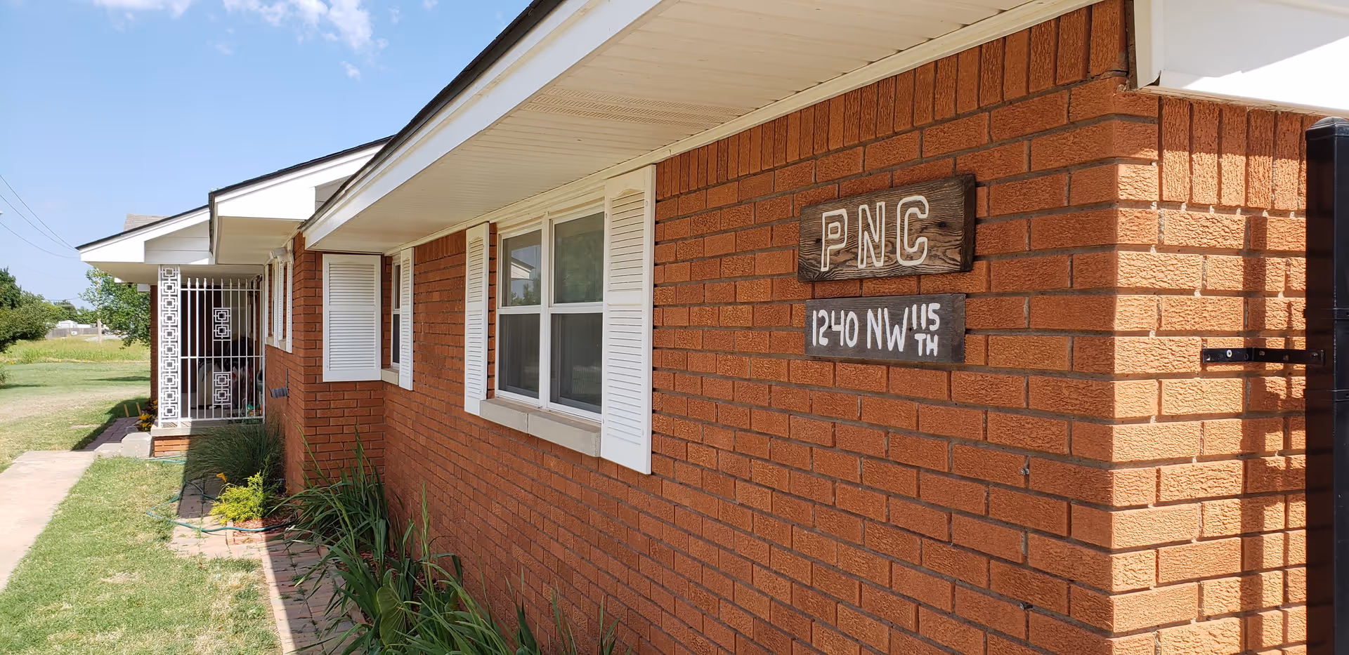 Brick, single-story senior facility exterior with PNC sign on wall.
