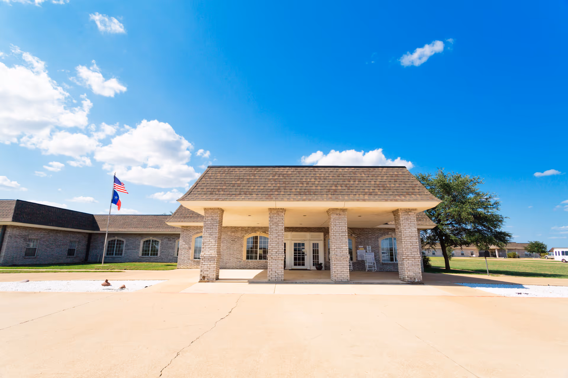 Front view of a brick care center with a covered entrance and flagpole under blue sky.