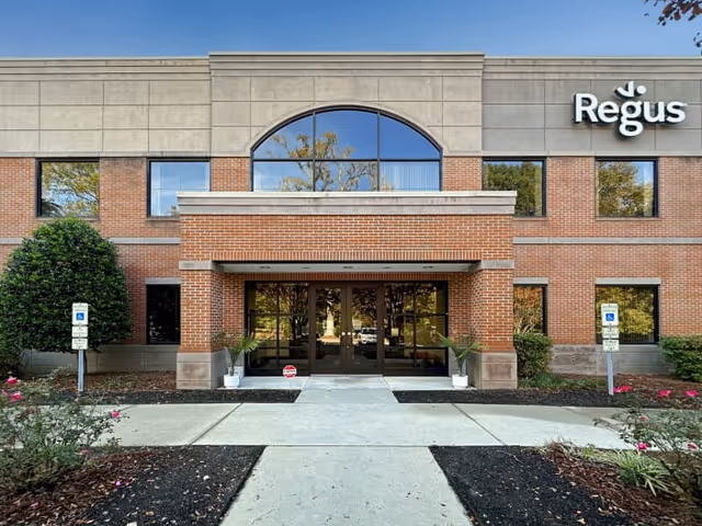 Exterior view of a senior living facility entrance with brick facade and glass doors.