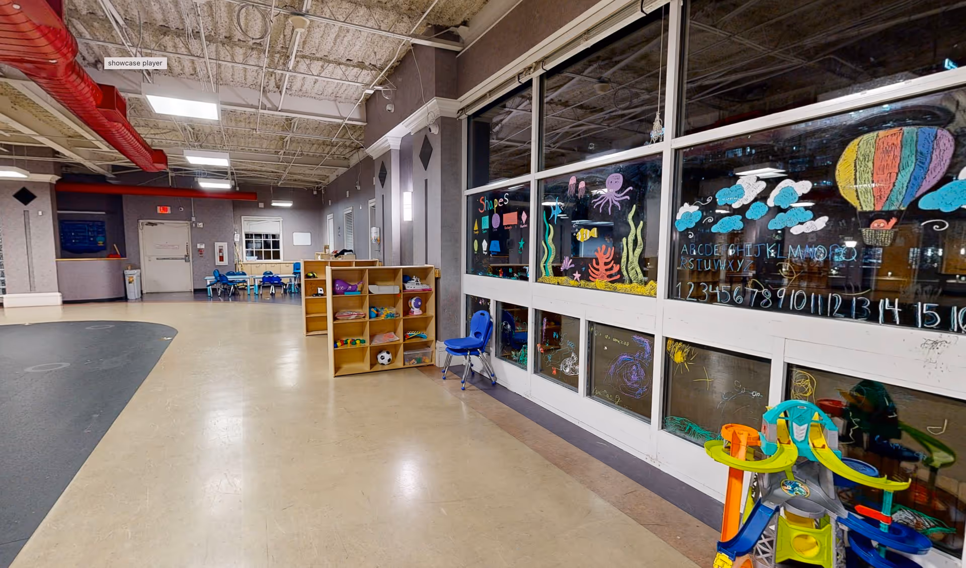 Bright indoor play area with shelves, toys, and colorful window chalk drawings.