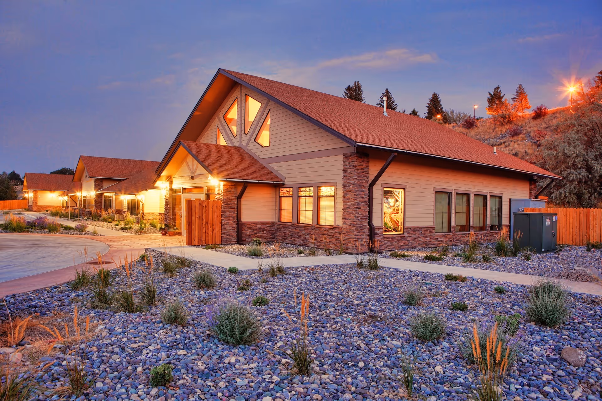 Twilight exterior view of Cody Regional Health Spirit Mountain Hospice House with a rocky landscape.