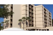 Mary Walker Towers exterior: beige high-rise with balconies, palm trees, and a white canopy in foreground.