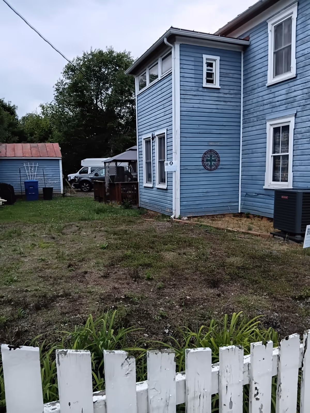 Exterior view of a blue Care Angels facility with white picket fence and yard.